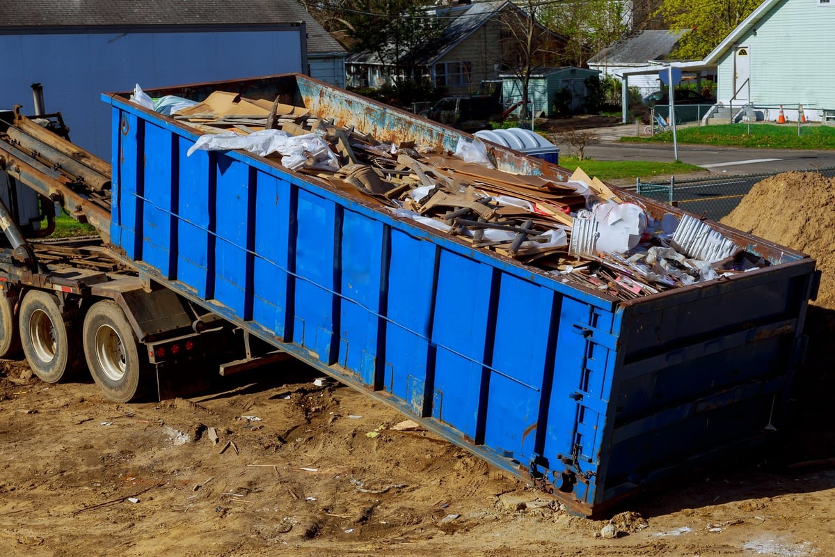 Truck loading a skip waste management container during a junk removal job