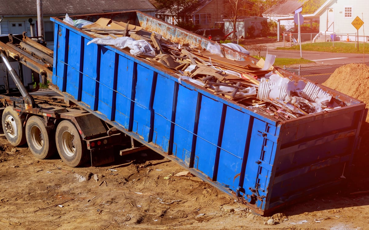 Industrial blue construction debris container filled with rock and concrete rubble